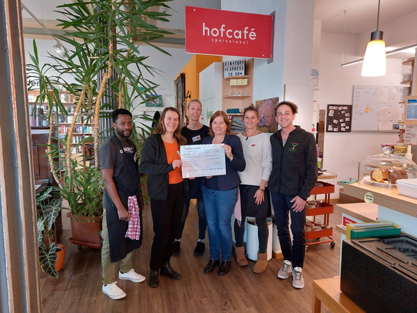 Mitarbeiter der Amperhof Ökokiste übergeben die gesammelten Kundenspenden an das hofcafé der Caritas.
