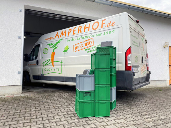 KI generiert: Lieferwagen mit "Amperhof.de" und "Ökokiste" Aufschrift, beladen mit grünen und grauen Kisten.