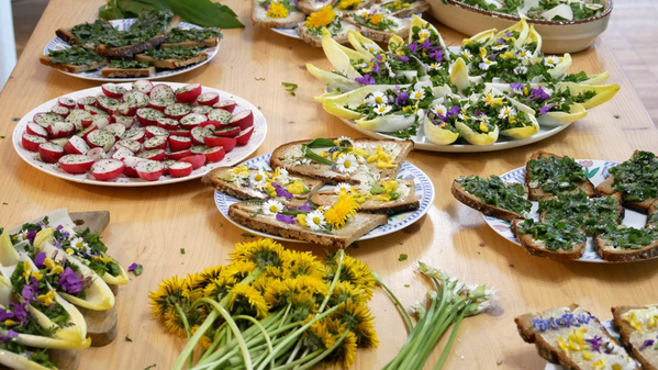 KI generiert: Verschiedene Teller mit belegten Broten und Salaten, dekoriert mit essbaren Blumen auf einem Tisch.