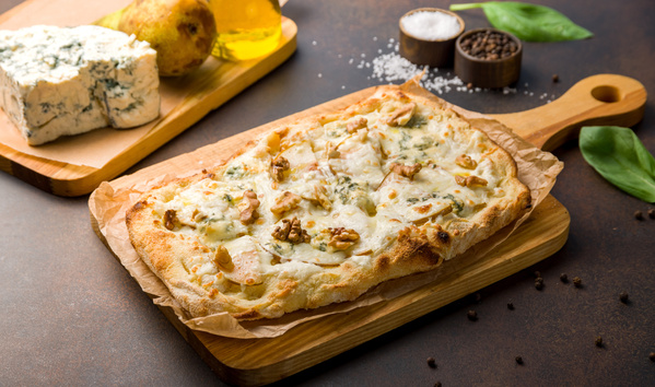 KI generiert: Flammkuchen mit Käse und Nüssen auf Holzbrett, daneben Käse und Birnen.
