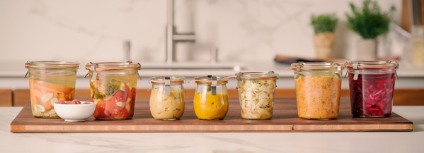 KI generiert: Ein Brett mit verschiedenen Gläsern voller eingelegtem Gemüse.