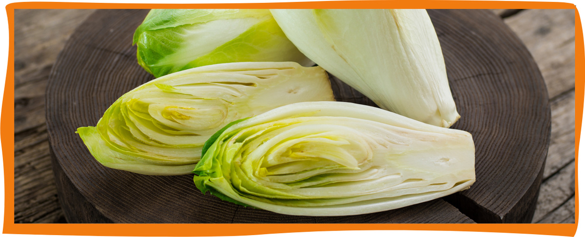 KI generiert: Geschnittener Chicorée liegt auf einem runden Holzbrett.