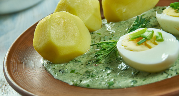 KI generiert: Gekochte Kartoffeln und halbe Eier auf grüner Soße, garniert mit Kräutern auf einem braunen Teller.