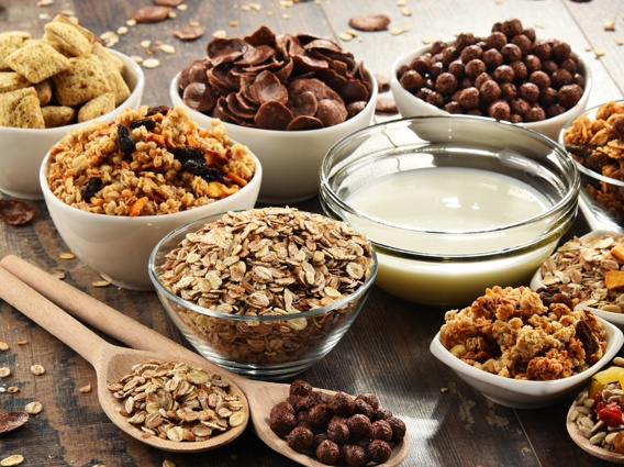 KI generiert: Verschiedene Sorten Cerealien in Schalen, darunter Müsli, Haferflocken und Schokomüsli, mit Milch in einer Schale.