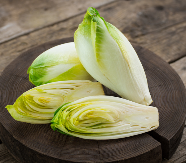 KI generiert: Frische Chicorée-Äpfel auf einem rustikalen Holzbrett.