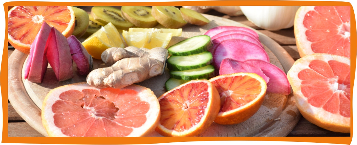 KI generiert: Auf dem Bild sind verschiedene geschnittene Früchte und Gemüse auf einem Holzbrett zu sehen, darunter Blutorange, Grapefruit, Kiwi, Ingwer, Gurke und Radieschen. Die Anordnung zeigt eine bunte und gesunde Auswahl an frischen Lebensmitteln.