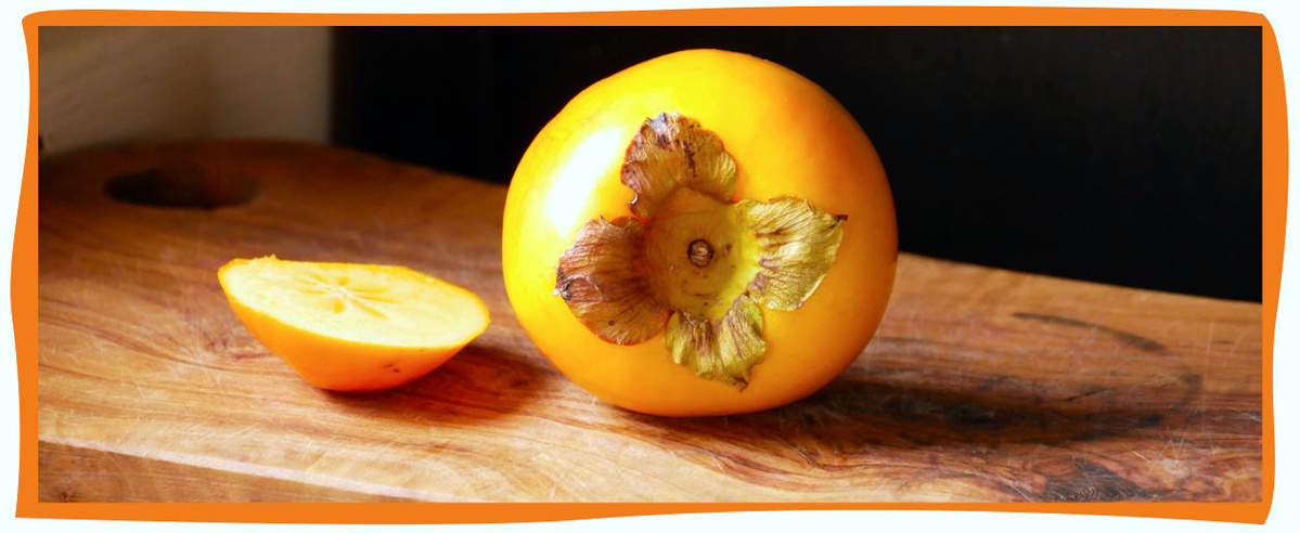 KI generiert: Eine ganze und eine halbierte Kaki-Frucht auf einem hölzernen Schneidebrett.