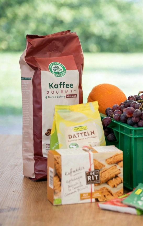 KI generiert: Lebensmittelarrangement mit Kaffee, Datteln, Keksen, Trauben und Orange. Text: "Kaffee Gourmet", "DATTELN".