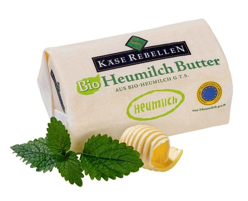 KI generiert: Packung Bio-Heumilchbutter mit frischen Kräutern und einer Butterspirale. Text: "Käse Rebellen, Bio Heumilch Butter".