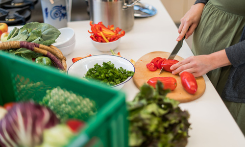 Eine Person schneidet frisches Bio-Gemüse aus der Ökokiste - Kochen mit der Ökokiste.