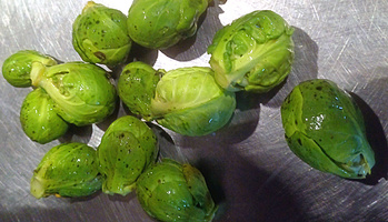 KI generiert: Das Bild zeigt frisch gewaschene Rosenkohlröschen auf einer Metalloberfläche. Sie sind gleichmäßig verteilt und glänzen leicht.